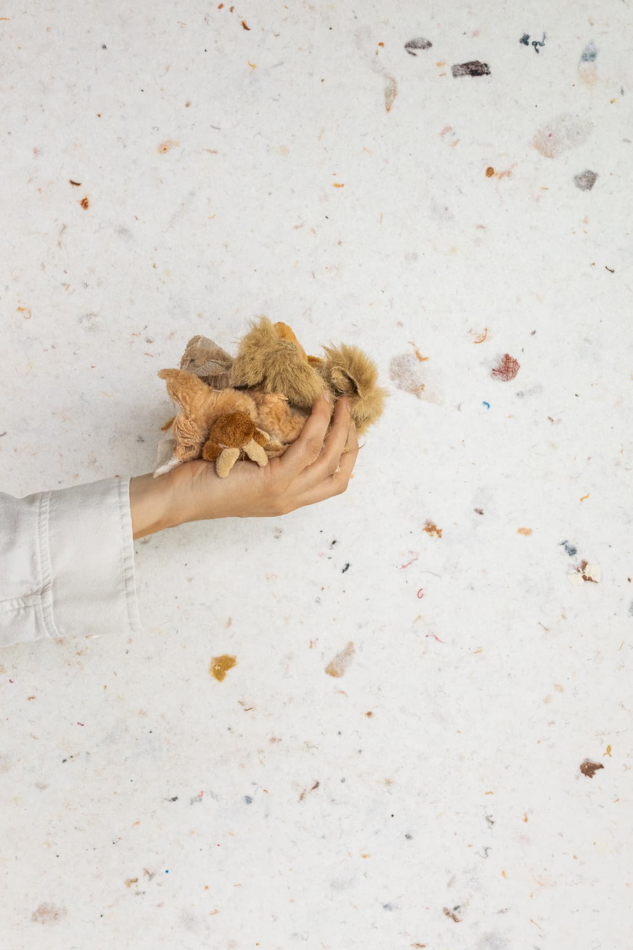 Main tenant des chutes de peluches au-dessus d'un feutre de fibres recyclées